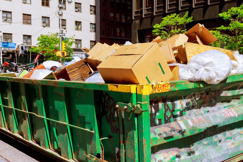 A dumpster overflowing with cardboard boxes, representing an outdoor junk removal service in Houston, TX.