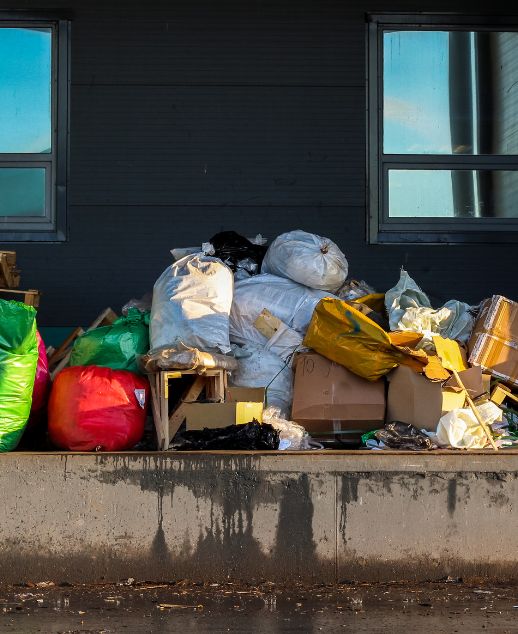 A collection of garbage bags and debris stacked outside a building, showcasing a junk removal service in Houston, TX.